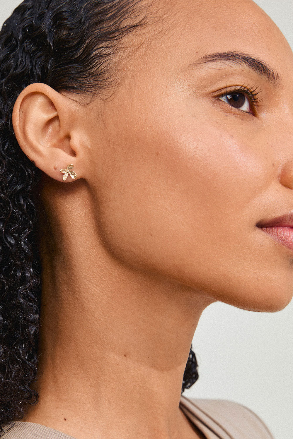 Photo of a woman wearing AGLAIA, a gold flower-shaped earring from Pilgrim La petite garçonne Montreal