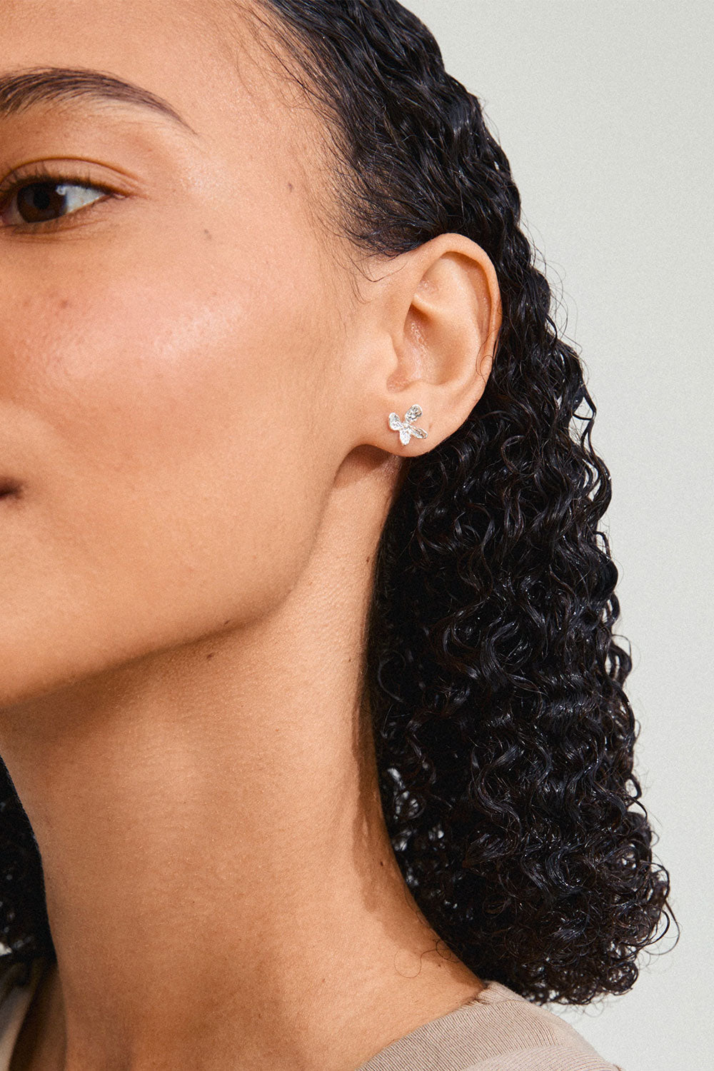 Close-up on a model wearing AGLAIA, a silver flower-shaped earring from Pilgrim La petite garçonne Montreal