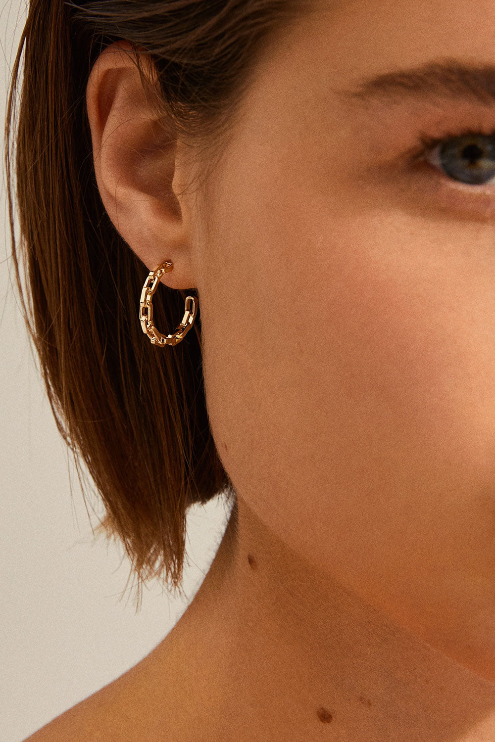 Close-up of a person wearing gold hoop earrings  Lumbini from Pilgrim available at la petite garçonne in Montreal