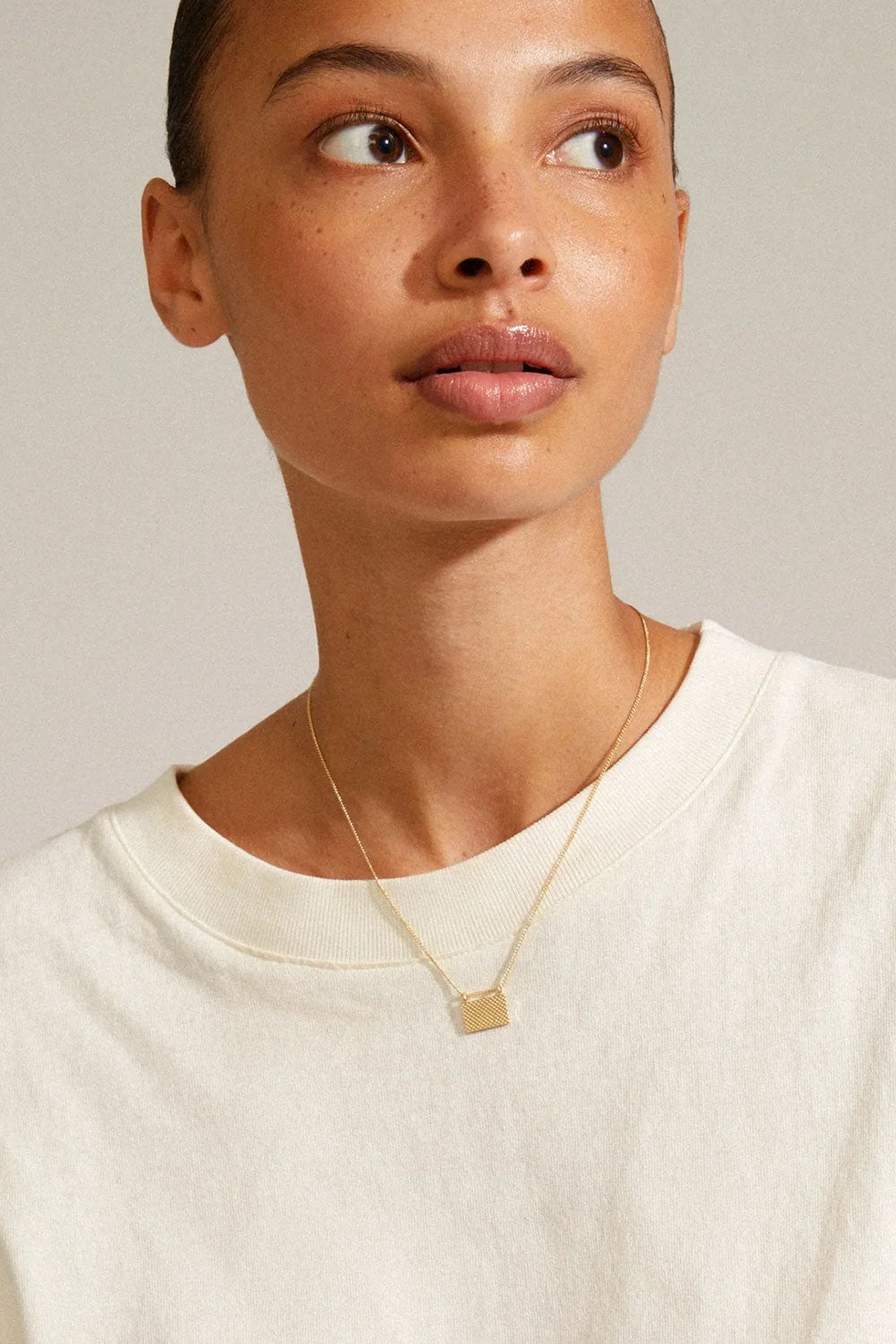 Pulse from Pilgrim, a gold necklace with a geometric pendant worn by a person. Available at la petite garçonne in Montreal