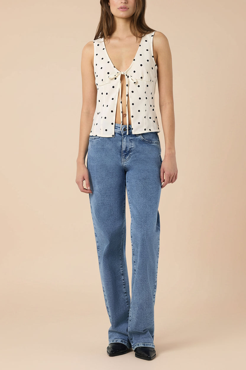 front view of a woman wearing Raisen Polka Dot Sleeveless White Top with Front Tie from La petite garçonne