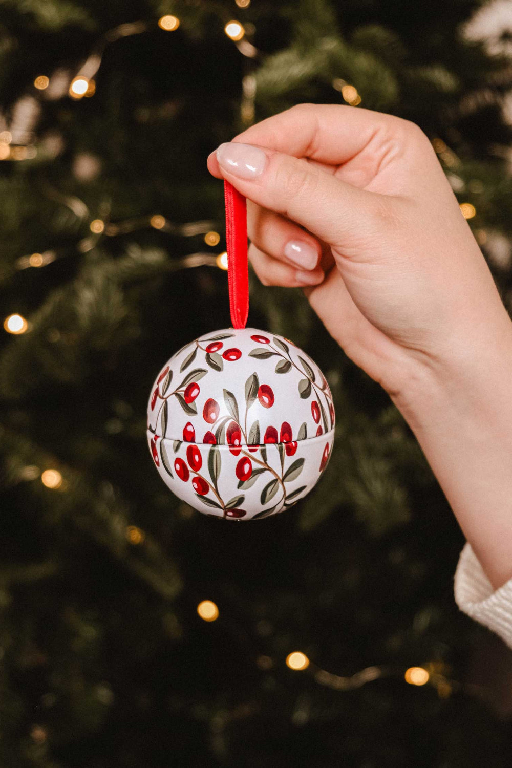 Spiced Cranberries Christmas Ornament by Mimi & August on a wooden surface, surrounded by berries and leaves.