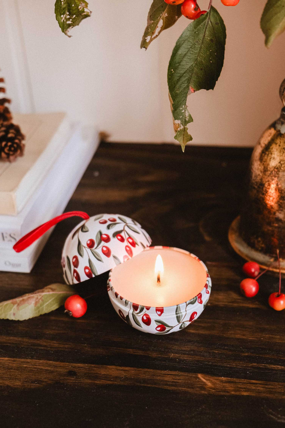 Spiced Cranberries Christmas Ornament by Mimi & August on a wooden surface, surrounded by berries and leaves.