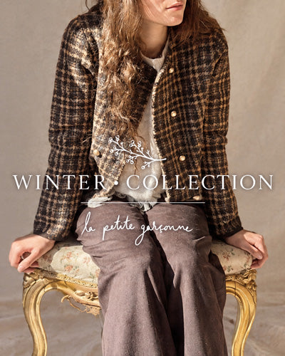 A woman seated on an ornate gold chair wearing a brown and beige plaid tweed jacket over a cream top and taupe wide-leg trousers. Large overlaid text reads 'WINTER COLLECTION' and 'la petite garçonne boutique'.