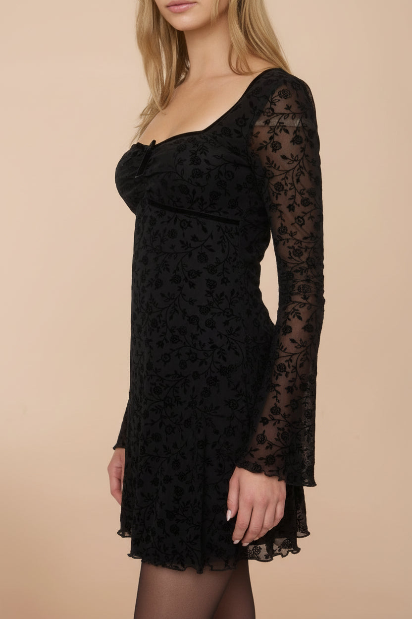 Sideview of a woman wearing a Zoeline Short Long-Sleeved Black Dress from boutique 1861
