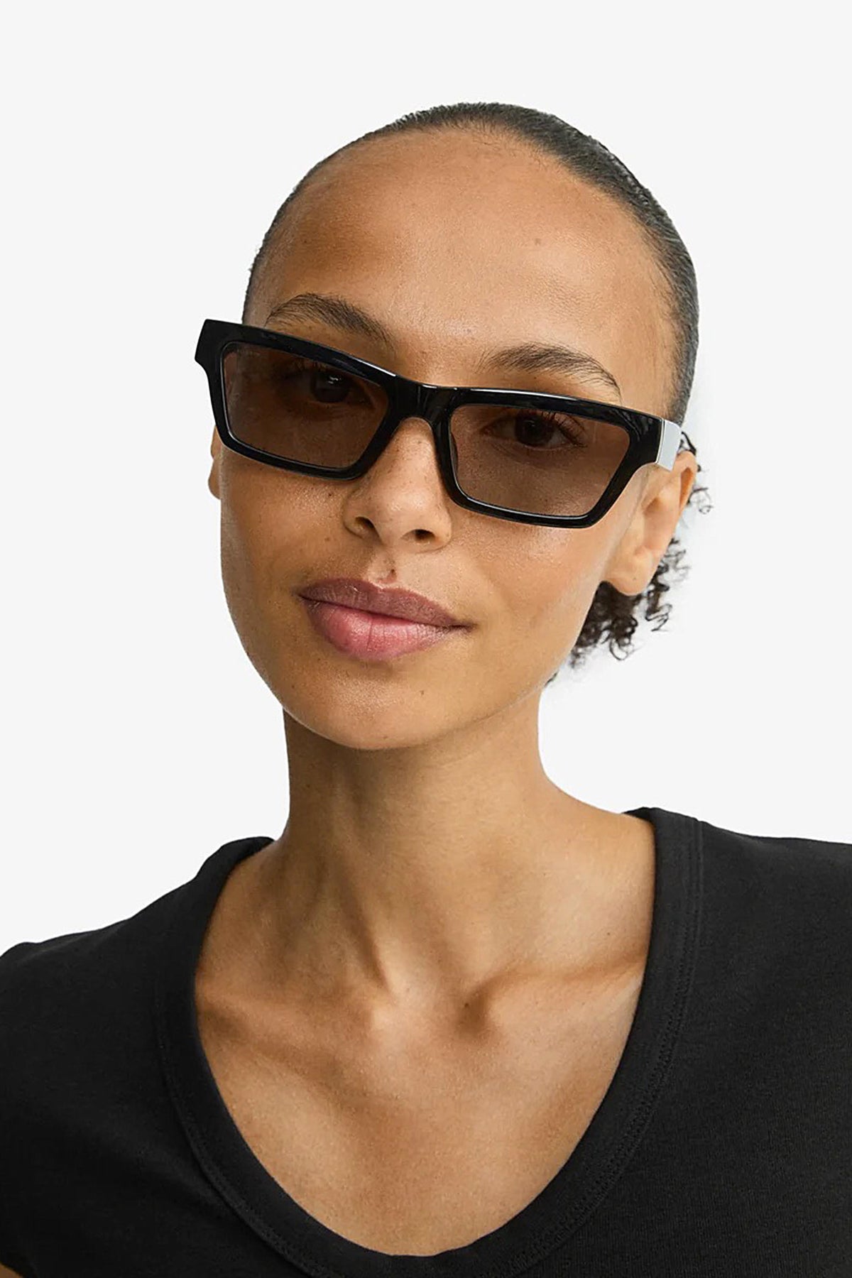 front of a woman wearing Crema Black Rectangle Frame Sunglasses by Pilgrim from La petite garçonne