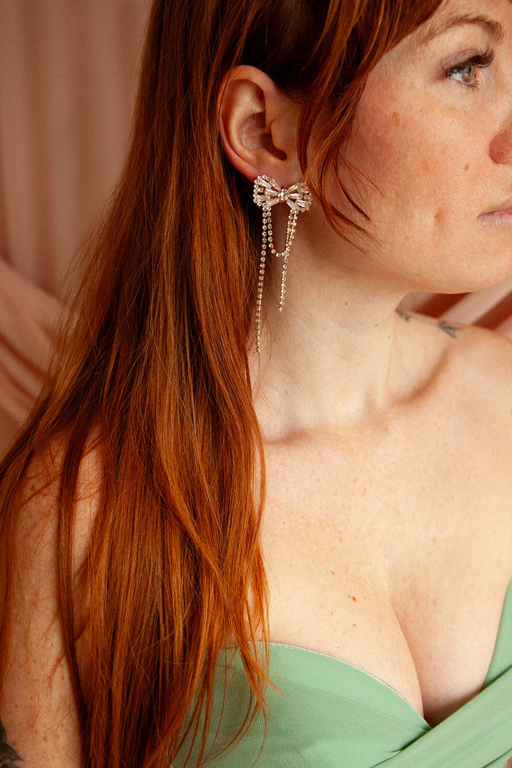 woman wearing Dolaricia Gold Bow Earrings with Pendant Chains from Boutique 1861 