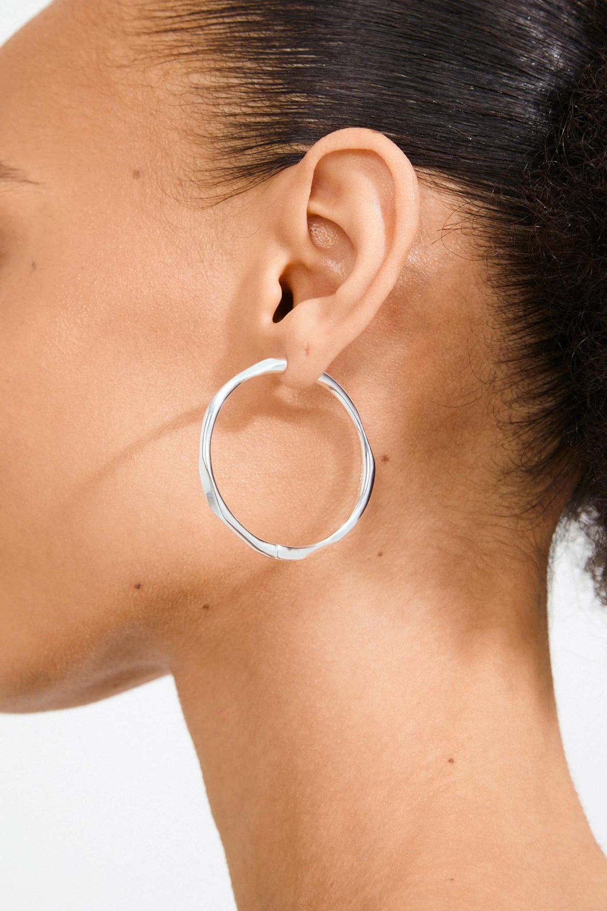 close-up of a woman wearing Edelia Silver Wave Hoop Earrings by Pilgrim from La petite garçonne