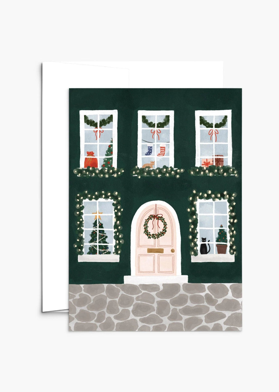 Christmas-themed greeting card from Mimi & August with a house facade, windows, and door decorated with lights and wreaths on a green background.