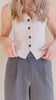 Video of a a mannequin is wearing the light gray vest Indio with dark buttons, standing against a plain beige background.